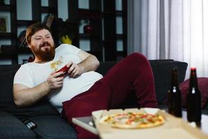 gordo feliz com uma camisa suja jogando videogame foto