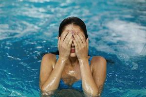 garota cobrindo os olhos na piscina foto