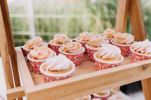 cupcakes gourmet com cobertura de creme de manteiga branco e confeitos em fundo de madeira foto