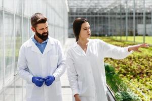 dois pesquisadores em vestes de laboratório caminham ao redor da estufa foto