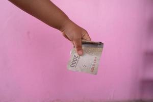 foco seletivo na nota de duas mil rupias indonésias mantida por uma garota asiática foto