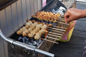 foco seletivo em satay de intestino de frango e almôndegas grelhadas no espeto de bambu e vendidas em festivais culinários. grelhado sobre carvão de madeira foto