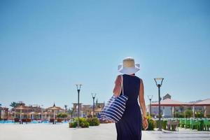 mulher de chapéu e vestido azul dar um passeio no hotel resort foto