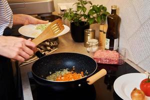 mulher cozinhando molho à bolonhesa na cozinha foto