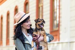 mulher hipster feliz brincando com seu cachorro na rua. menina estilosa com cachorro engraçado descansando, abraçando e se divertindo, momentos fofos. espaço para texto foto