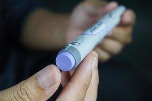 homem asiático com pele morena escura segurando a caneta de insulina. equipamento médico é fácil de auto-injeção foto