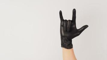 eu te amo sinal de mão e mão usar luva de látex preto sobre fundo branco. foto