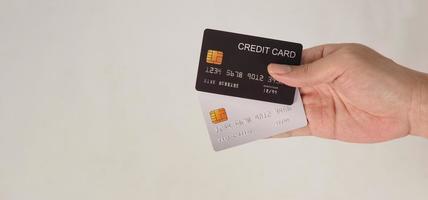 a mão segura dois cartões de crédito. cartões de crédito de cor preto e prata isolados no fundo branco. foto