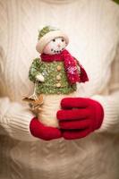 mulher vestindo luvas vermelhas sazonais segurando boneco de neve de natal foto