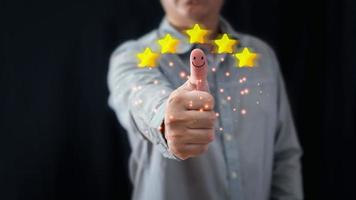 um homem de negócios polegares para cima no ícone de rosto sorridente feliz e cinco estrelas para dar satisfação no serviço. classificação muito impressionada. atendimento ao cliente e conceito de satisfação foto