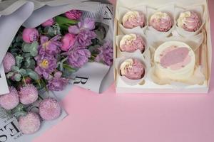 um lindo buquê e cupcakes estão na mesa rosa foto