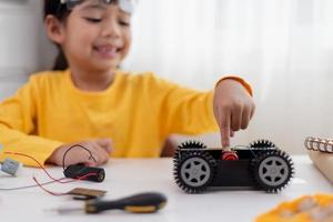 os alunos da ásia aprendem em casa na codificação de carros robóticos e cabos de placa eletrônica em haste, vapor, código de computador de tecnologia de ciência de engenharia matemática em robótica para o conceito de crianças. foto