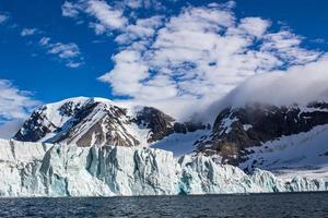 uma geleira com montanhas cobertas de neve atrás em svalbard foto