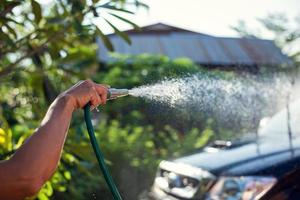 mão segurando a mangueira de lavagem de carro foto