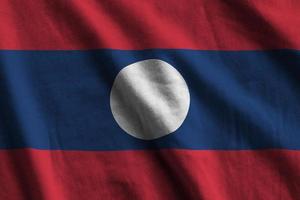 bandeira do laos com grandes dobras acenando de perto sob a luz do estúdio dentro de casa. os símbolos oficiais e cores no banner foto