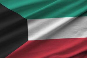 bandeira do kuwait com grandes dobras acenando perto sob a luz do estúdio dentro de casa. os símbolos e cores oficiais no banner foto