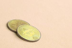 dois bitcoins dourados estão em um cobertor feito de tecido de lã laranja claro macio e fofo. visualização física da moeda criptográfica virtual foto