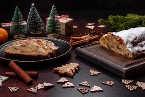 Stollen de torta de natal com maçapão, frutas e nozes em um fundo escuro de concreto foto