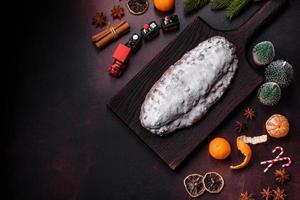 Stollen de torta de natal com maçapão, frutas e nozes em um fundo escuro de concreto foto