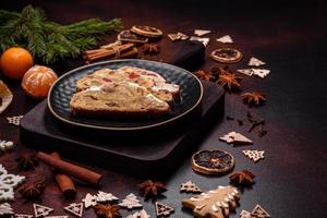 Stollen de torta de natal com maçapão, frutas e nozes em um fundo escuro de concreto foto