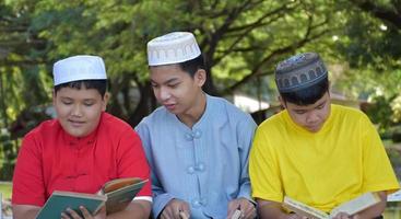 grupo de meninos muçulmanos sentam-se juntos sob a árvore no parque da escola, eles também leem, aprendem, conversam, sugerem e consultam problemas de aprendizagem uns aos outros, foco suave e seletivo. foto