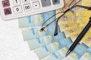 1 fã de notas de hryvnia ucraniano e calculadora com óculos e caneta. empréstimo comercial ou conceito de temporada de pagamento de impostos foto