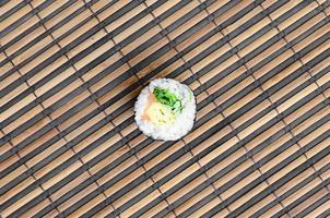 rolo de sushi deitada em uma esteira de serragem de palha de bambu. comida asiática tradicional. vista do topo. minimalismo plano leigo com espaço de cópia foto