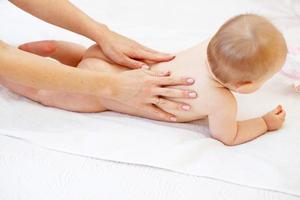 mãe massageando bebê na cama em casa foto