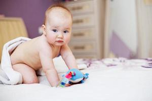 bebê fofo olhando para a câmera sob uma toalha branca. retrato de uma criança fofa foto