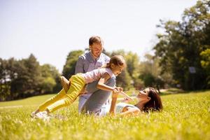 família jovem e feliz com a filhinha se divertindo no parque em um dia ensolarado foto