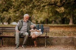 avô passar tempo com sua neta no banco no parque em dia de outono foto