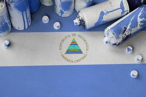 bandeira da nicarágua e algumas latas de spray aerossol usadas para pintura de graffiti. conceito de cultura de arte de rua foto