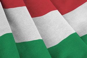 bandeira da Hungria com grandes dobras acenando de perto sob a luz do estúdio dentro de casa. os símbolos oficiais e cores no banner foto