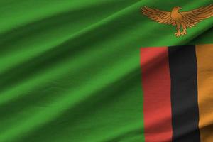 bandeira da zâmbia com grandes dobras acenando perto sob a luz do estúdio dentro de casa. os símbolos e cores oficiais no banner foto