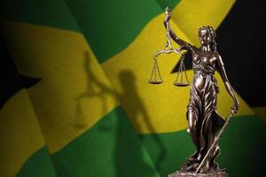 bandeira da jamaica com a estátua da justiça e balança judicial em quarto escuro. conceito de julgamento e punição foto