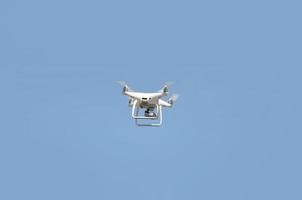 grande drone branco pairando em um céu azul brilhante e sem nuvens foto