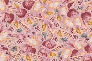 Notas de 50 pesos mexicanos estão em grande pilha. fundo conceitual de vida rica foto