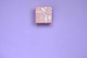 pequena caixa de presente rosa está no fundo de textura de papel de cor violeta pastel de moda em conceito mínimo foto