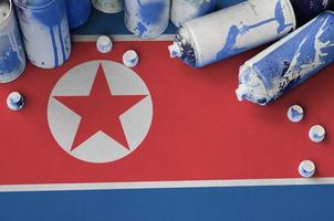 bandeira da coreia do norte e algumas latas de spray aerossol usadas para pintura de grafite. conceito de cultura de arte de rua foto