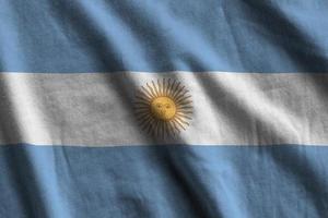 bandeira da argentina com grandes dobras acenando de perto sob a luz do estúdio dentro de casa. os símbolos oficiais e cores no banner foto