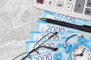 Notas de 2000 rublos russos e calculadora com óculos e caneta. empréstimo comercial ou conceito de temporada de pagamento de impostos. hora de pagar impostos foto