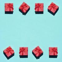quadro de muitas pequenas caixas de presente rosa vermelhas em fundo de textura de papel de cor azul pastel na moda no conceito mínimo. padrão abstrato foto