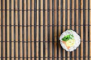 rolo de sushi deitada em uma esteira de serragem de palha de bambu. comida asiática tradicional. vista do topo. minimalismo plano leigo com espaço de cópia foto