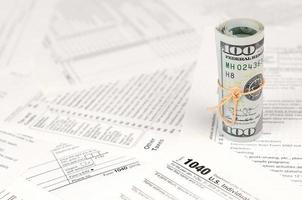 1040 formulário de declaração de imposto de renda individual com rolo de notas de dólar americano foto