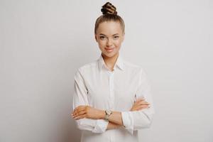 gerente feminina confiante na camisa branca com braços cruzados foto