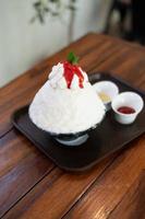 sobremesa de gelo raspado coreano com coberturas doces, morango bingsu na mesa de madeira foto