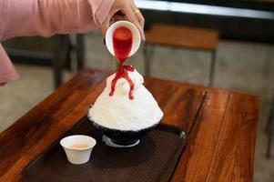 sobremesa de gelo raspado coreano com coberturas doces, morango bingsu na mesa de madeira foto