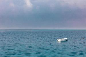 serenidade, barco solitário no mar azul. bela paisagem marítima com horizonte e céu foto