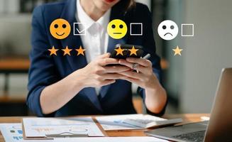 conceito de avaliação de serviço ao cliente. empresária pressionando show de emoticons de sorriso na tela virtual no tablet e smartphone foto