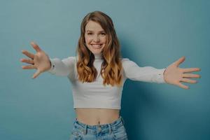 jovem mulher positiva feliz em roupas casuais abrindo os braços no desejo de receber alguém foto